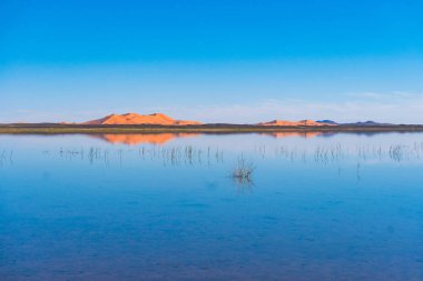 Erg Chebbi'nin kum tepeleri ve bir gölün yansıması. Merzouga kasabası yakınlarında çekilen manzara fotoğrafı, Sahra Çölü, Fas