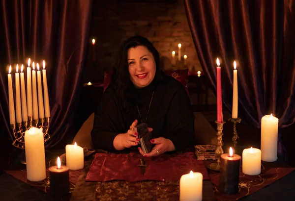 Cajero de la fortuna mujer en habitación oscura con un montón de adivinanzas velas en una baraja de cartas del tarot — Foto de Stock