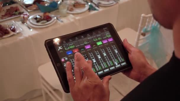 Mixeur audio, tablette ipad. L'homme tient une tablette numérique dans ses mains, contrôlant le niveau sonore. Réglage des paramètres sonores du groupe de musique — Video
