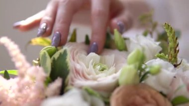 Kız yavaşça parmaklarına güzel bir çiçek buketi dokunur. Yakından kapatın. İyi bir ruh hali