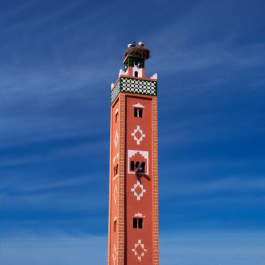 Eski geleneksel terracotta minaresinin tepesinde leylek yuvası ve penceresinden Arap adam süsü çiziyor. Fas, çöl