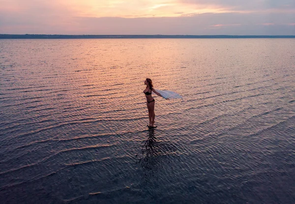 Silhouette d'une fille au milieu du lac au coucher du soleil. Belle fille posant seule en eau peu profonde avec des ondulations légères — Photo