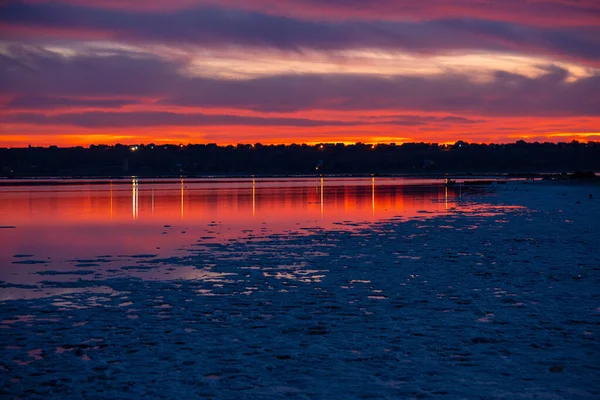 Hermosa vista de crepúsculo de Kuyalnik liman con el tráfico y la luz de la ciudad que refleja en aguas tranquilas de firth con nubes de color rojo brillante después de la puesta del sol. Odessa, Ucrania — Foto de Stock
