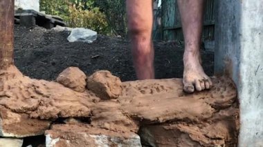 Çıplak ayakla kilden bir ev inşa ederken yakın plan bir çekim.