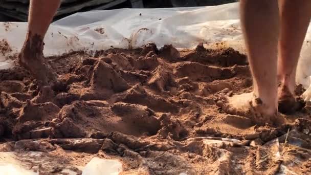 어도비 에어 브릭으로 간단 한 집을 짓기 위해 맨 발로 찰흙을 반죽하는 모습을 가까이 서 찍은 사진 — 비디오