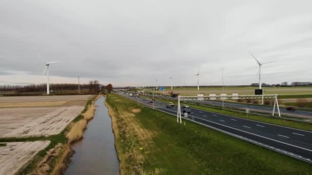 Fila de aerogeneradores en los Países Bajos en el día nublado en una autopista de vehículos Amsterdam - Rotterdam . — Vídeo de stock