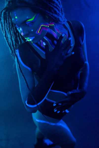 Cocky Girl com Dreadlocks em luz de néon ultravioleta com fundo Foggy. Bodyart. — Fotografia de Stock