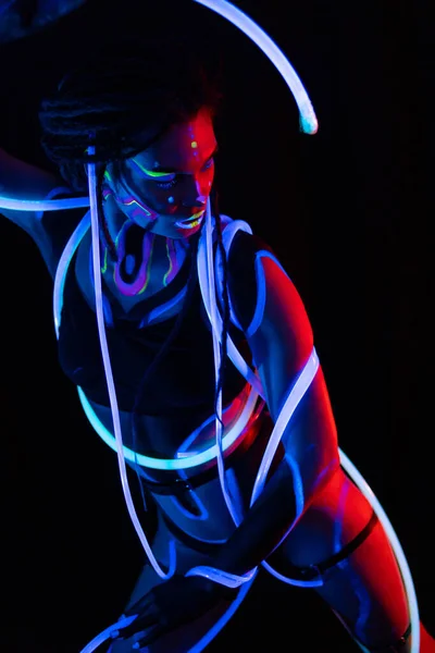 Porträtt av en krigarflicka med glödande rör i Neon UF Light. Modell flicka med dreadlocks och fluorescerande kreativ psykedelisk makeup, Art Design av kvinnliga disco dansare modell i UV, färgglada abstrakt — Stockfoto