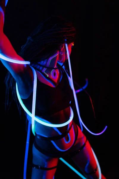 Ritratto di una ragazza guerriera con tubi luminosi nella luce al neon UF. Modello Ragazza con Dreadlocks e Fluorescente Creativo Trucco Psichedelico, Art Design della Danzatrice di Discoteca Femminile Modello in UV, Colorato Astratto — Foto Stock