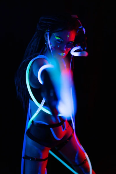 Retrato de uma garota de guerra com tubos brilhantes em Neon UF Light. Menina modelo com Dreadlocks e maquiagem psicodélica criativa fluorescente, Design de arte do modelo de dançarina de disco feminino em UV, abstrato colorido — Fotografia de Stock