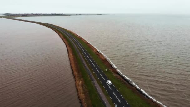 Voo aéreo tiro de carro branco movendo-se pela estrada da estrada na barragem na Holanda conectando o continente com uma ilha de Marken na Holanda — Vídeo de Stock