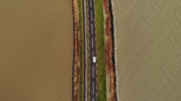 Luftaufnahme eines weißen Autos, das sich auf der Autobahn auf dem Damm in den Niederlanden bewegt, der das Festland mit einer Insel der Marken in Holland verbindet — Stockvideo