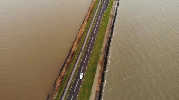 Αεροφωτογραφία του Λευκού αυτοκινήτου που κινείται από την εθνική οδό στο φράγμα στην Ολλανδία που συνδέει την ηπειρωτική χώρα με ένα νησί Marken στην Ολλανδία — Αρχείο Βίντεο