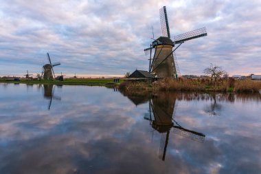 Kinderdijk Holland 'daki ünlü yel değirmenlerinin üzerinde dramatik bulutlu bir gökyüzü. Güneşli bir yaz akşamı, yel değirmeni köyünün kırsalında. Hollanda, UNESCO Dünya Mirası Bölgesi. Kinderdijk Yel Değirmeni Köyü