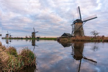 Kinderdijk Holland 'daki ünlü yel değirmenlerinin üzerinde dramatik bulutlu bir gökyüzü. Güneşli bir yaz akşamı, yel değirmeni köyünün kırsalında. Hollanda, UNESCO Dünya Mirası Bölgesi. Kinderdijk Yel Değirmeni Köyü