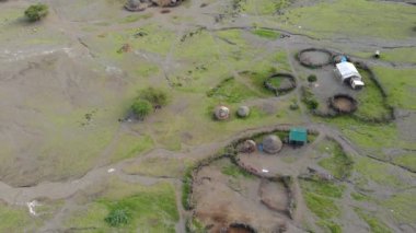 Günbatımında Afrika 'nın kuzey Tanzanya bölgesindeki Arusha Bölgesi' nde Engare Sero köyü Maasai dilinde Tanrı 'nın Dağı Ol Doinyo Lengai' nin önündeki Maasai köyü üzerinde Uçan Sinek Manzarası.