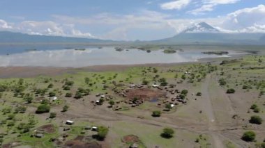 Natron Gölü kıyısındaki Maasai köyünde, Maasai dilinde Tanrı 'nın Dağı, Kuzey Arusha Bölgesi' nde Engare Sero köyü, Ol Doinyo Lengai 'nin önünde Uçan Sinek Manzarası.