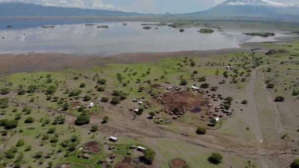 Flyby lotnicze Widok na wioskę Maasai na wybrzeżu jeziora Natron przed Ol Doinyo Lengai, Góra Boga w języku maasai, Engare Sero wsi w regionie Arusha i północnej — Wideo stockowe