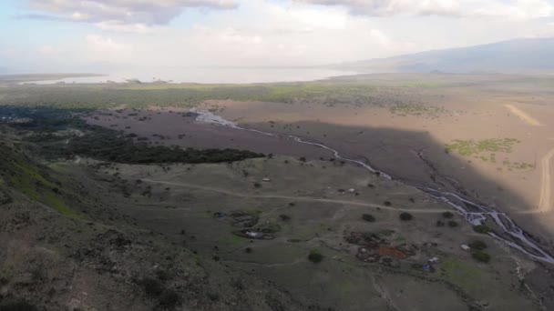 Flyby lotnicze Widok na wioskę Maasai na wybrzeżu jeziora Natron przed Ol Doinyo Lengai, Góra Boga w języku maasai, Engare Sero wsi w regionie Arusha i północnej — Wideo stockowe