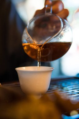Geleneksel Çin Çay Seremonisi. Siyah ya da kırmızı çay, arka planda beyaz pial fincana dökülüyor.