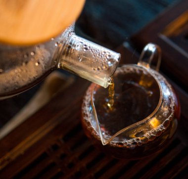 Geleneksel Çin Çay Seremonisi. Siyah ya da Kırmızı Çay, Büyük Cam Çaydanlıktan, Siyah Tahta Masa Arkaplanındaki Cam Chahai 'ye dökülüyor