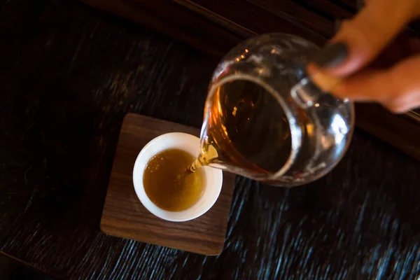 伝統的な中国茶の儀式。黒または赤の紅茶が濃いテーブルの上に白いペアカップに注ぐ背景 — ストック写真