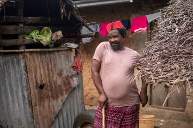Kızıl Müslüman Takiyyah Fez Şapkalı Afrikalı yaşlı bir adam, Tanzanya 'nın Küçük Uzak Köyü' nde, Pemba Adası 'nda, Zanzibar' da çatısı Thatched olan, Yard 'da topal insanlar için sopayla poz veriyor.