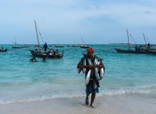 Nungwi, Sansibar, Tansania, Afrika - Januar 2020: Schwarzafrikanischer Mann trägt Thunfisch auf dem Straßenfischmarkt im Dorf Nungwi, die Menschen kaufen den Fisch im öffentlichen Verkauf. Versteigerung von — Stockfoto