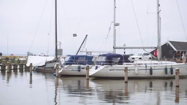Many sailing yachts parked in the port of Marken with masts reflecting to a water in cloudy misty Day — Stock Video