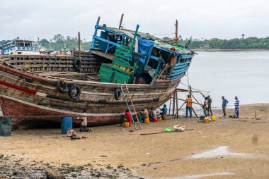 DAR ES SALAAM, TANZANIA - 2020 HAZİRAN: Dar Es Salaam Liman Koyu kıyısında tahtadan balıkçı teknesi tamir eden Afrikalı siyahi grup