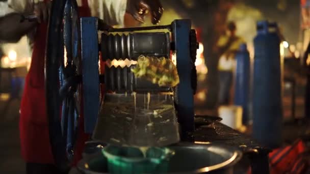 Un uomo nero africano strizza una canna da zucchero al Forodhani Night Street Market per produrre succo fresco e biologico con uno spremiagrumi alimentato a mano. Prodotto sano da un venditore ambulante di Zanzibar — Video Stock