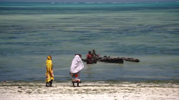 Jambiani, Zanzibar, Tanzanie, DÉCEMBRE 2019 : Femme tanzanienne locale sur la plage, avec bateau de pêche et mer dans le backgorund, marée basse. — Video