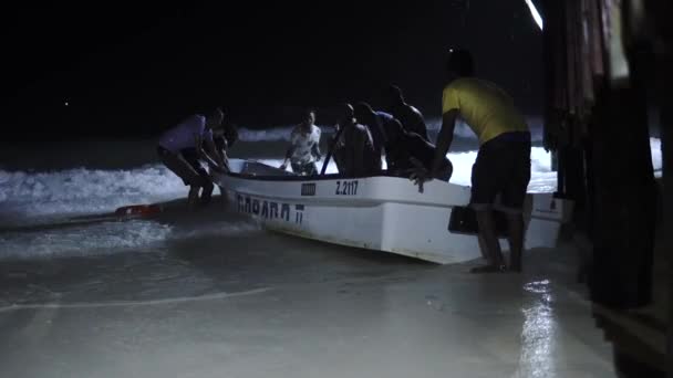 NUNGWI, ZANZIBAR - JAN 2020: Tropische nachtstorm op Zanzibar. Groep van zwarte Afrikaanse mensen redden van de motorboot uit een stormachtige oceaan Scoop uit een water met emmer — Stockvideo