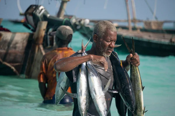 Nungwi, Sansibar, Tansania, Afrika - Januar 2020: Schwarzafrikanischer Mann trägt Thunfisch auf dem Straßenfischmarkt im Dorf Nungwi, die Menschen kaufen den Fisch im öffentlichen Verkauf. Versteigerung von — Stockfoto