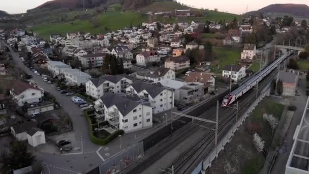Vue aérienne d'un train qui va et vient dans un petit village en Suisse — Video
