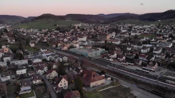 Luchtfoto van de trein komt en gaat door een klein dorp in Zwitserland — Stockvideo