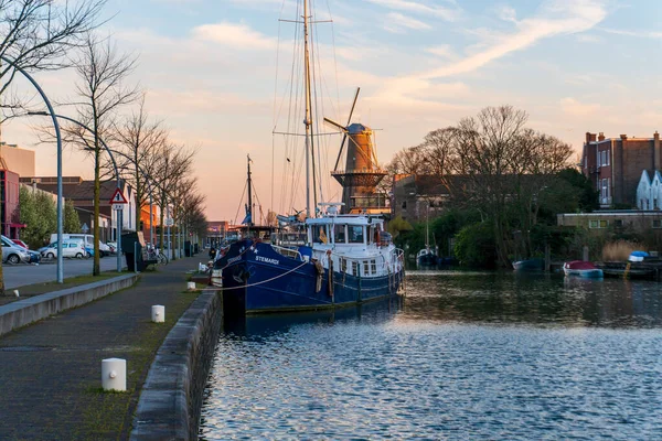 Twilight efter solnedgången skott av högsta väderkvarn i världen och Vessel på förgrunden i Schiedam, Nederländerna är känd för sina väderkvarnar och även JWhen, en typ av gin — Stockfoto