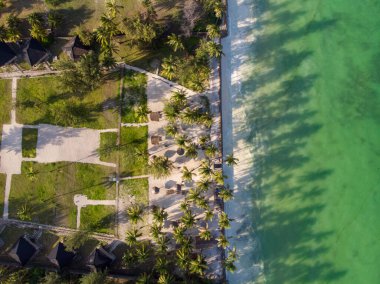 Palmiye ağaçlarıyla dolu bir sahilde lüks bir otelin havadan çekilmiş fotoğrafı, akşam vakti Tanzanya 'nın Zanzibar kentindeki Paje köyünde Hint Okyanusu' nun yüksek gelgit suyuna gölgelerini düşürüyor.
