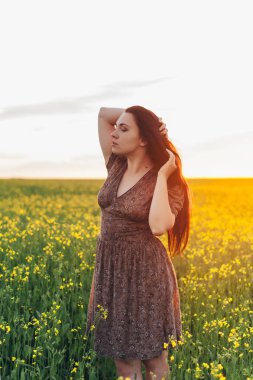 Alanında gün batımında güzel genç kadın