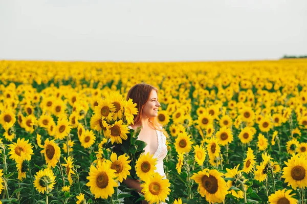 Schöne Mädchen in einem riesigen gelben Feld von Sonnenblumen. — Stockfoto