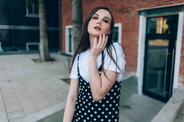 Uzun siyah sarafan güzel bir kız sokakta yürür. 