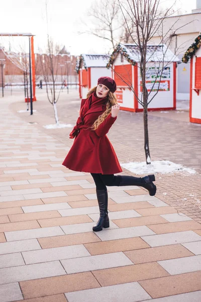 Красивая девушка в красном пальто и берете идет вдоль — стоковое фото