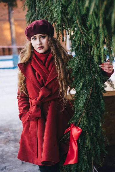 Ένα όμορφο κορίτσι με ένα κόκκινο παλτό και ένα μπερέ περπατάει κατά μήκος του — Φωτογραφία Αρχείου