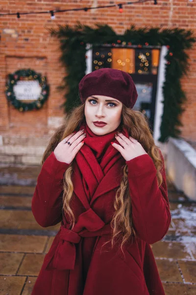 Красивая девушка в красном пальто и берете идет вдоль — стоковое фото