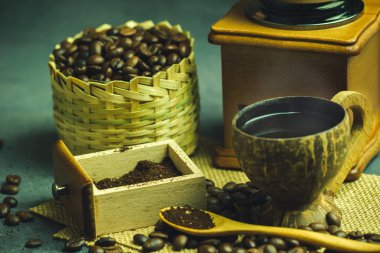 Yakın plan kahve, hindistan cevizi fincanı ve sabah aydınlatması. Bambu sepetinde kavrulmuş kahve çekirdekleri ve tahta kaşık. Klasik kahve öğütücüsü ve moka demliği. Sabah kahve zamanı kavramı mı yoksa yeni güne başlamak mı?.