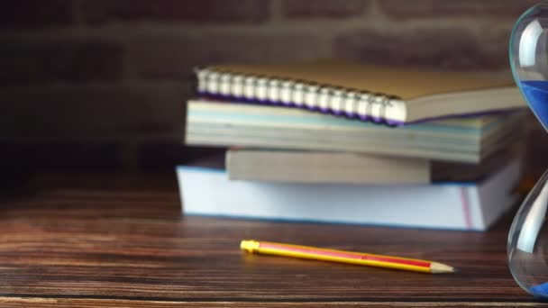 多利沙漏与铅笔和书籍堆叠在木桌上 学习和教育的概念 — 图库视频影像