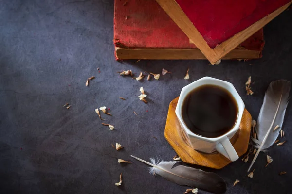 Schwarzer Kaffee in weißer Tasse und alte Bücher mit Feder und getrocknetem f — Stockfoto