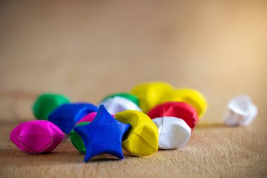 Çoklu renkli kağıt yıldız, sabah güneşiyle ahşap masaya serilmiş.