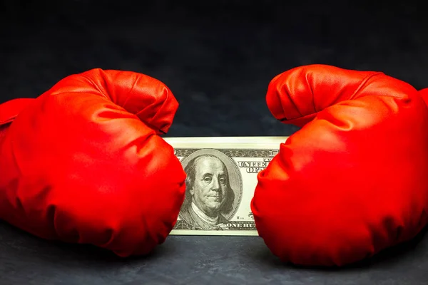 Kırmızı boks eldivenleri çimento katında dolar banknot tutan.
