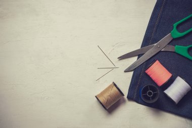 Beyaz ahşap zeminüzerinde dikiş araçları ve ekipmanları.